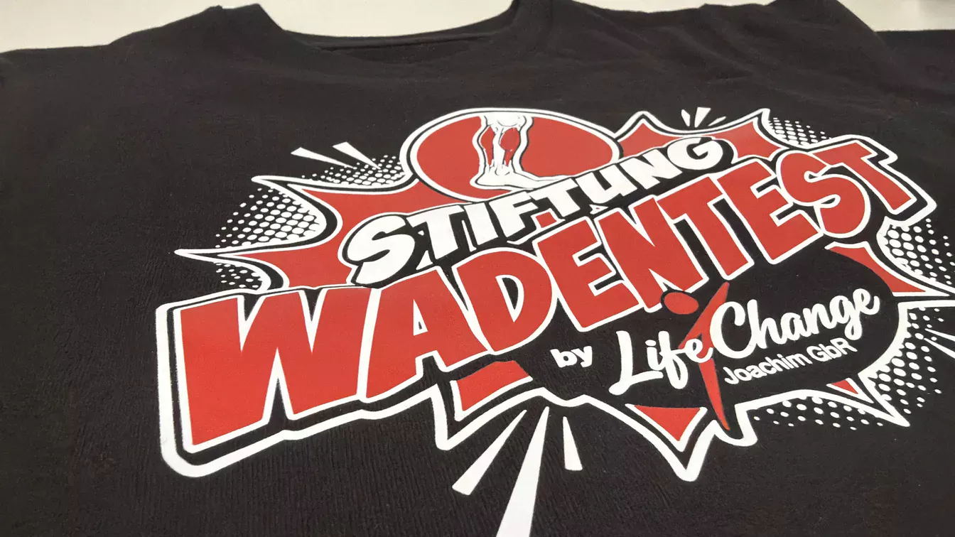 Mehrfarbig veredeltes schwarzes Shirt mit Stiftung-Wadentest-Motiv von Life Change Joachim GbR