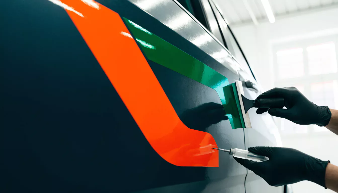 Konzeptionelle Nahaufnahme einer präzisen Fahrzeugfolierung in Orange und Grün